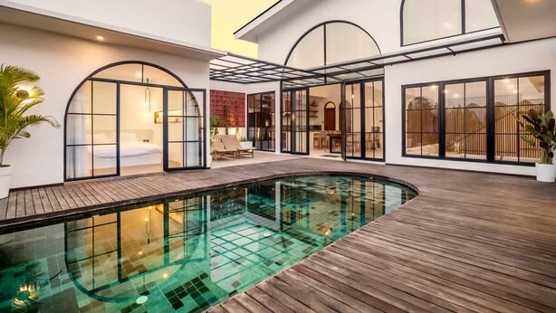 Uma casa moderna com piscina, janelas amplas e um deck de madeira.