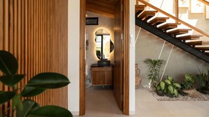 Ein Flur mit Holztür, Waschbecken und Treppe.
