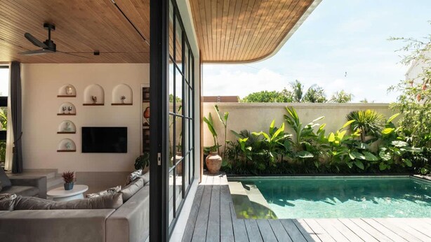 Ein moderner Außenbereich mit Pool, Holzterrasse und einer Sitzecke mit Sofa und Couchtisch.