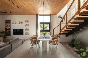 A modern living room with a dining table, sofas, a staircase, and a TV mounted on the wall. - Ben s Villa 1 in Kuta Utara (Kuta Utara)