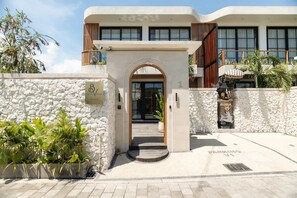 A hotel entrance with a stone facade, an archway, and a sign indicating parking. - Ben s Villa 1 in Kuta Utara (Kuta Utara)