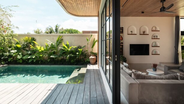 Un'area esterna moderna con piscina, terrazza in legno e zona salotto con divano e tavolino.