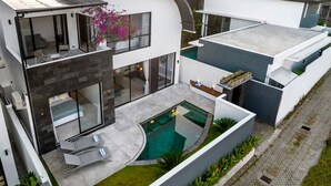 Un moderno edificio residencial de varios pisos con piscina, ventanas amplias y una zona de patio.