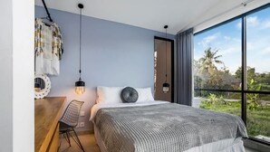 Un dormitorio moderno con una cama grande, una silla colgante y vistas al verdor exterior.