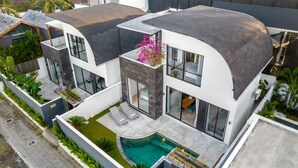 Una casa moderna con techo curvo, piscina y jardín.