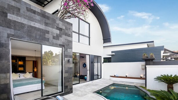 Una casa moderna con piscina, puertas de vidrio que dan a un dormitorio y techo curvo.