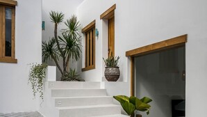 Un bâtiment moderne aux murs blancs, doté de fenêtres à cadre en bois et d’un escalier menant à une porte.