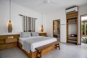 A modern bedroom with a wooden bed, bedside tables, a bench, a wardrobe, and a ceiling fan. - Villa Oasi 2 in Kecamatan Kuta Selatan (Kecamatan Kuta Selatan)