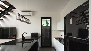 Una cocina moderna con encimera negra, horno integrado y refrigerador negro.