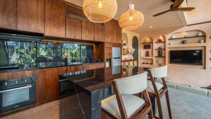 A modern kitchen with wooden cabinets, a large island, and pendant lighting. - The Mystik Loft Nirvana (Pererenan)