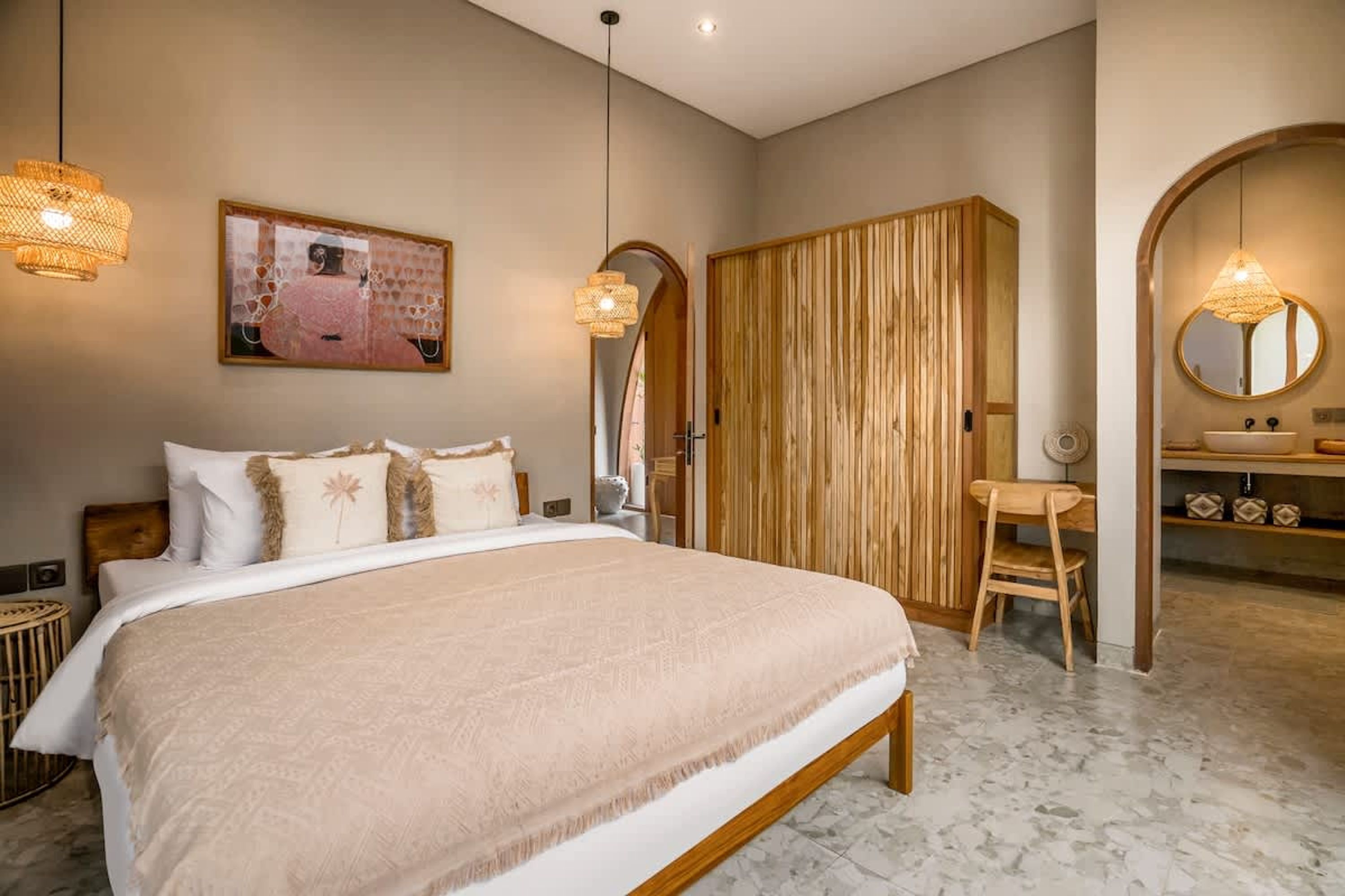 Un dormitorio con una cama grande, un armario de madera, un escritorio y un baño con espejo y lavamanos.