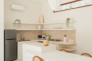 A modern kitchen with a refrigerator, microwave, sink, and white cabinetry. - Villa Sari 2 in Bingin Beach (Bingin Beach)