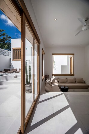 Un intérieur moderne avec une grande fenêtre, un ventilateur de plafond et un canapé.