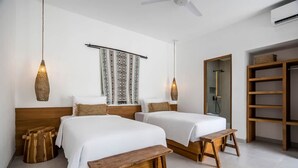 Ein Schlafzimmer mit zwei Betten, einer hölzernen Bank, einem Teppich und einem Deckenventilator sowie einem Kleiderschrank.