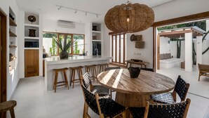 Una cucina moderna con un'isola centrale, sedie di legno e un tavolo da pranzo rotondo.