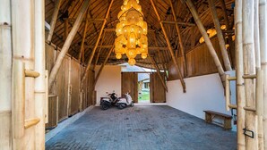 An interior with a bamboo structure, a scooter, and a bench. - 2BR Villa Bily in South Kuta (South Kuta)