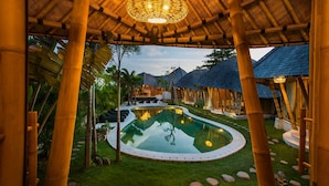 A pool surrounded by bamboo structures, a clear sky, and a well-maintained lawn. - 2BR Villa Bily in South Kuta (South Kuta)
