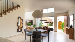 Ein modernes Interieur mit Essbereich, Treppe und großen Fenstern.