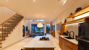 Eine moderne Küche mit Kochinsel, Holzschränken und einem schwarzen Kühlschrank.