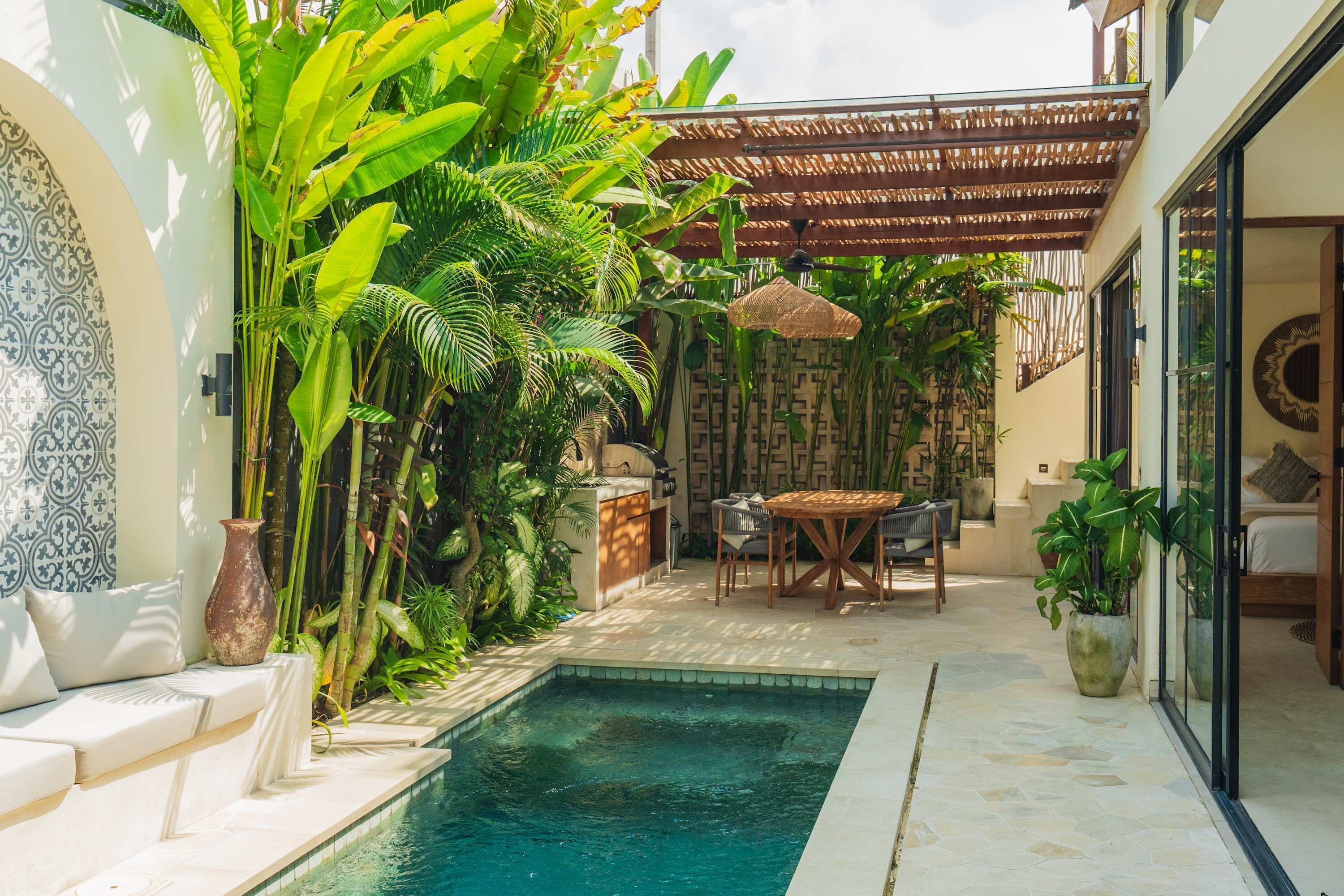 A pool area with a seating area, a table, and various plants.