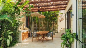 Un espace extérieur abrité comprenant une piscine, une table à manger avec des chaises et une végétation luxuriante.