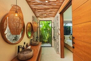 A bathroom with a wooden vanity, a large mirror, and a view of a tropical garden. - Villa Rasa Rasa in Mengwi (Mengwi)