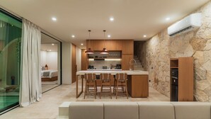 A modern kitchen with a central island, wooden cabinets, and pendant lighting. - Villa Kalani Soul in South Kuta (South Kuta)