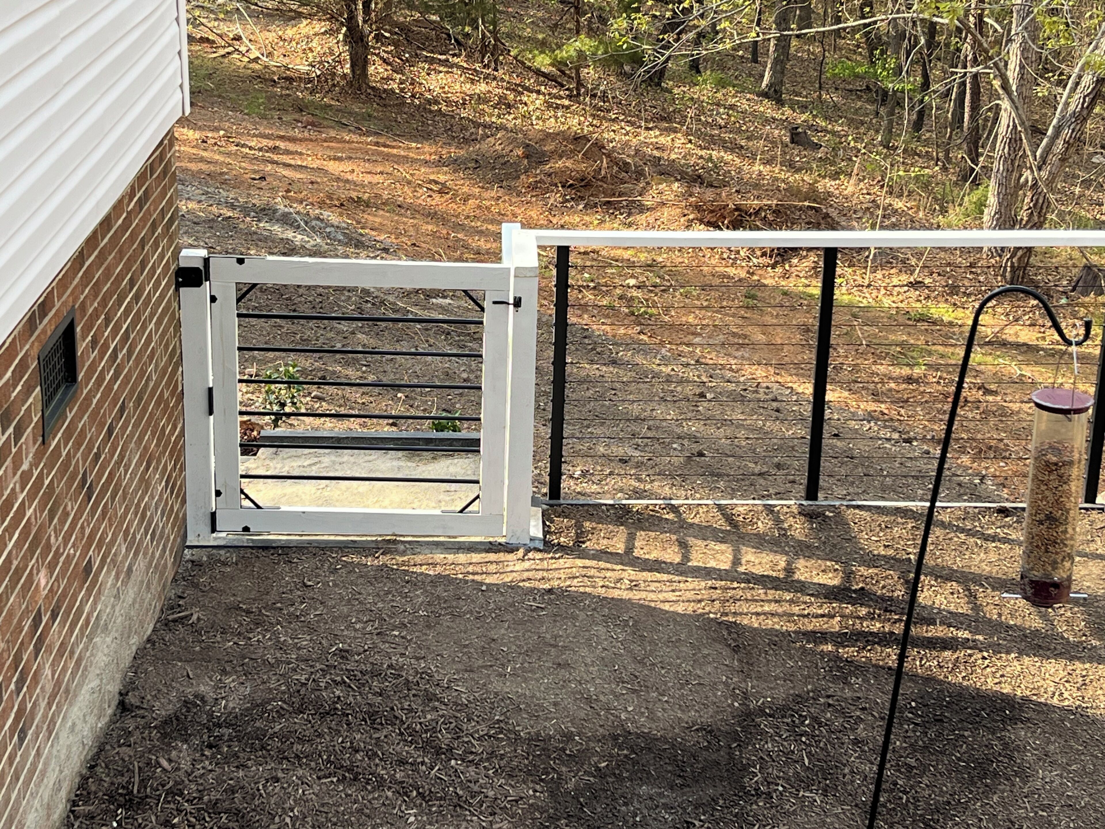A gated area with a metal gate, a brick wall, and a wooden fence.