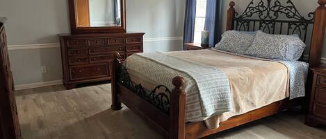 Un dormitorio con cama de madera, cómoda, espejo y silla.