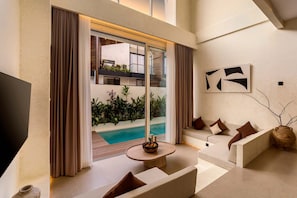 A modern living room with a pool view, a flat-screen TV, and a minimalist decor. - Villa Fresko 2 in Mengwi (Mengwi)
