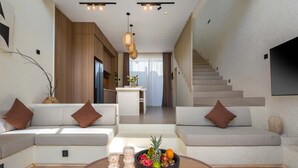 Ein modernes Wohnzimmer mit einer Couch, einem Couchtisch mit Früchten und einer Treppe.