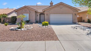 A residential house with a garage, a driveway, and a landscaped front yard with rocks and plants.