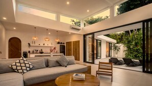 Una sala de estar moderna con un sofá, una mesa de centro y una zona de estar con vistas a zonas verdes.