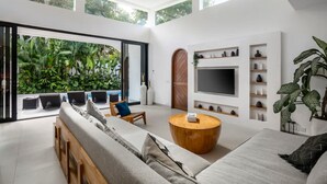 Una sala de estar moderna con un televisor grande, una mesa de centro de madera y un sofá.