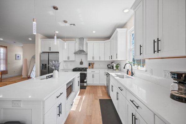 A modern kitchen with white cabinetry, a central island, and a large window providing natural light.