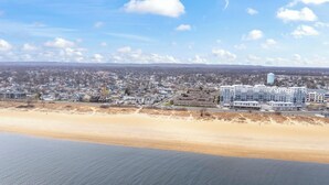 A coastal town with residential buildings, a beach, and a distant mountain range.