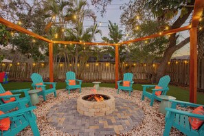 Eine Terrasse mit Feuerstelle, Sitzgelegenheiten und Lichterketten.