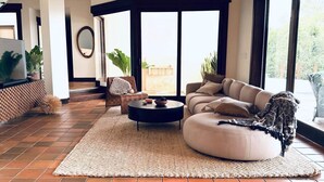 A modern living room with a sofa, coffee table, and a large window. - Villa Las Brisas: Ocean View and Walk to the Beach (Sámara)