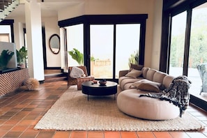 A modern living room with a sofa, coffee table, and a large window. - Villa Las Brisas: Ocean View and Walk to the Beach (Sámara)