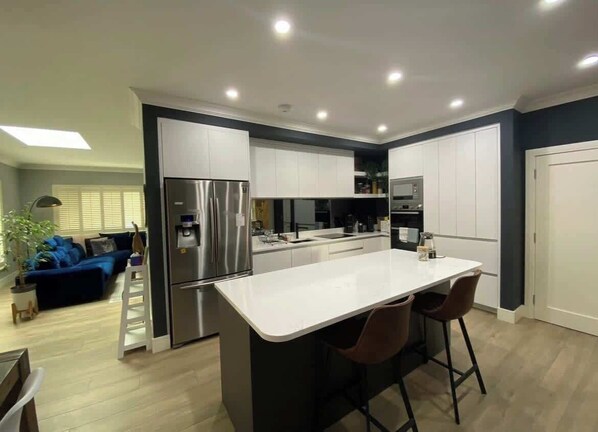 A modern kitchen with white cabinets, stainless steel appliances, and a central island with bar stools.