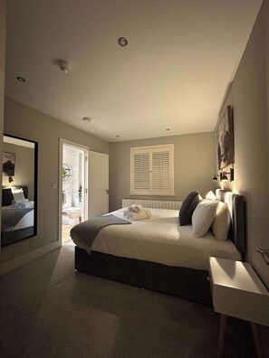 A bedroom with a bed, bedside table, and a window with shutters.