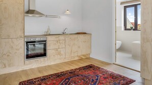 A modern kitchen with wooden cabinets, a built-in oven, and a window overlooking the city. - 4 Star Holiday Home in Lokken (Lokken)