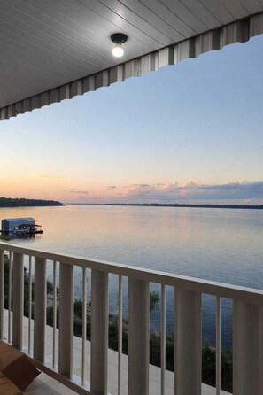 A balcony with a view of a calm body of water and a distant shoreline at sunset. - Hotel Star Rio (Novo Airão)