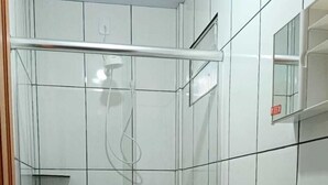 Un baño con inodoro, lavamanos y ducha con cerramiento de vidrio.