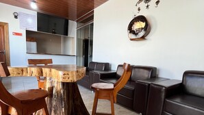 Un comedor con una mesa y sillas de madera, un sofá y un adorno en la pared.