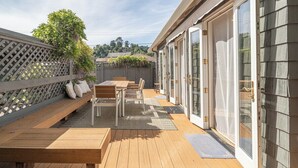 Eine Holzterrasse mit einer Bank und einem Tisch, einem Gitterzaun und einer Tür mit Glasfeldern.