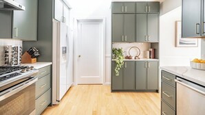 Eine moderne Küche mit grauen Schränken, einem weißen Kühlschrank und einem Holzboden.