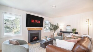 Ein Wohnzimmer mit Kamin, Flachbildfernseher und Sofa.