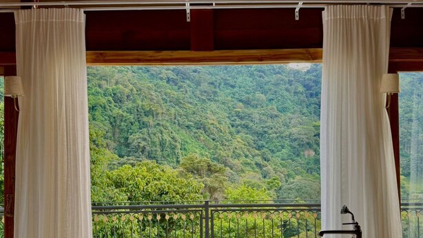 A large freestanding bathtub in a room with a view of a forested hillside. - Hacienda La Amalia (Venecia)