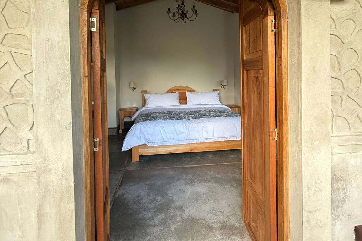 Un dormitorio con cama de madera, candelabro y pared de piedra.